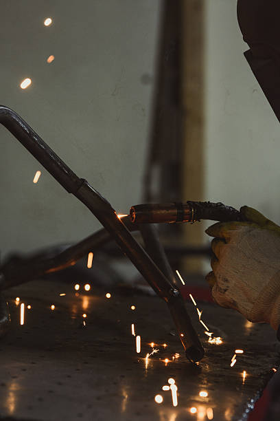 istock Industrial worker welding steel pipe, producing hot sparks and reflections 636574168