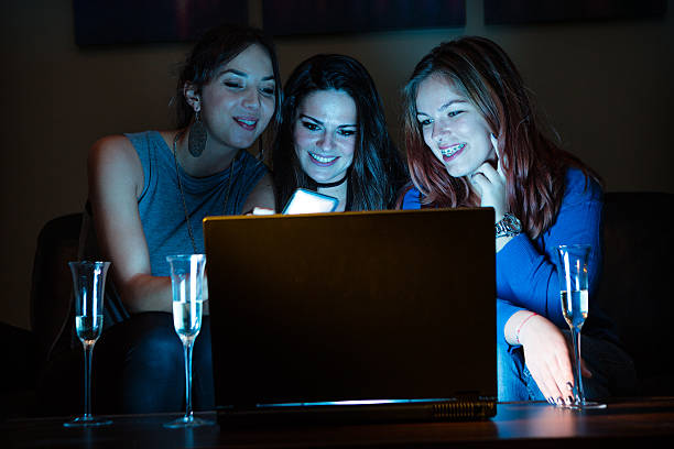 istock Three girlfriends, drinking champagne, watchng something interes 636576878