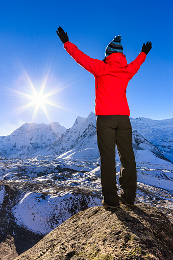 Young woman standing on the top of a mountain and watching sunrise over Himalayas, she is wearing red jacket. The rising sun on a background. Mount Everest National Park. This is the highest national park in the world, with the entire park located above 3,000 m ( 9,700 ft). This park includes three peaks higher than 8,000 m, including Mt Everest. Therefore, most of the park area is very rugged and steep, with its terrain cut by deep rivers and glaciers. Unlike other parks in the plain areas, this park can be divided into four climate zones because of the rising altitude. The climatic zones include a forested lower zone, a zone of alpine scrub, the upper alpine zone which includes upper limit of vegetation growth, and the Arctic zone where no plants can grow. http://bhphoto.pl/IS/nepal_380.jpg