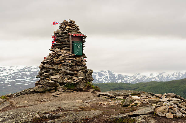 Stack of stones with Norway flags on the top of mountain in Lofoten, Norway. Mountains on the background