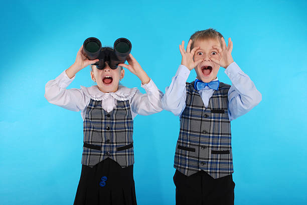 istock Schoolboy and schoolgirl playing with binoculars 636579378