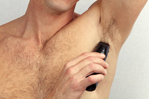 istock Male depilation. Man using trimmer to remove hair from armpit 636581596