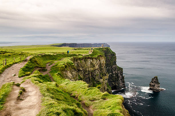 walking at the edge of ireland's cliff of moher - cliffs of moher cliff republic of ireland sea imagens e fotografias de stock