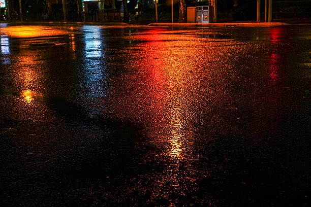 Rainy night in the big city Rainy night in the big city, light from the shop windows reflected on the road on which cars travel. View from the level of asphalt wet stock pictures, royalty-free photos & images