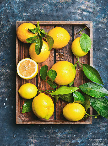 istock Freshly picked lemons with leaves in rustic wooden tray 636591766