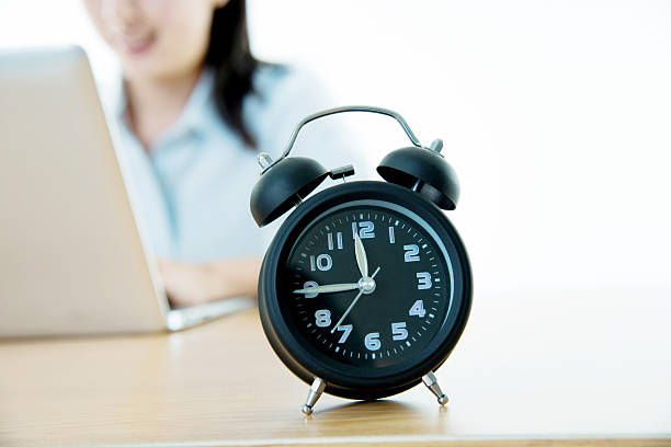 istock Businesswoman working on laptop with clock showing time 636593408
