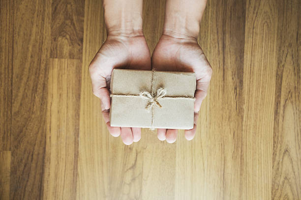 istock Asian male hand holding gift box, on wood texture backgorund 636595788