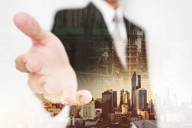 Businessman stretch out hand, with double exposure city and real estate site construction with workers