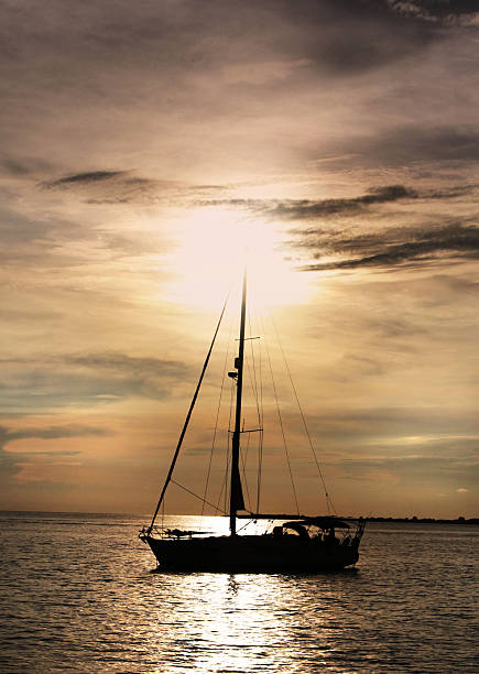 Sailboat at Sunset Sailboat anchored on calm waters with a brilliant sunset in the background. kingston harbour stock pictures, royalty-free photos & images