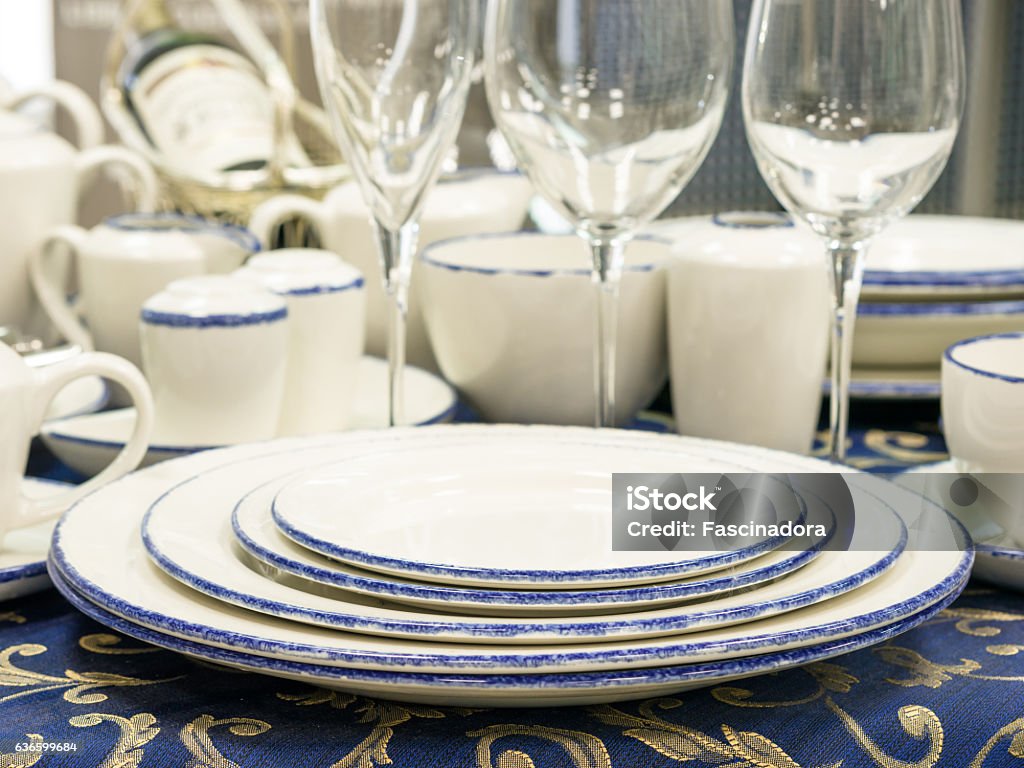 Set of dishes on table Set of new dishes on table with blue tablecloth. Stack of plates, saucer and wine glasses on restaurant table. Shallow DOF Alcohol - Drink Stock Photo