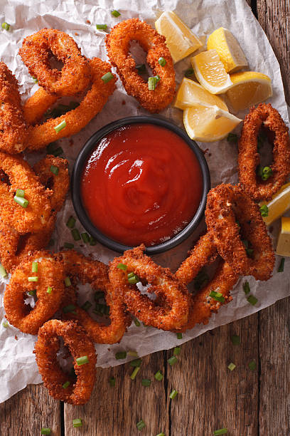 istock crunchy fried squid rings with ketchup and lemon close-up. Vertical 636600332