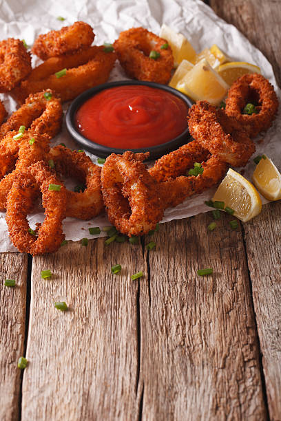 istock Fried calamari close-up on a table, and tomato sauce. Vertical 636600450