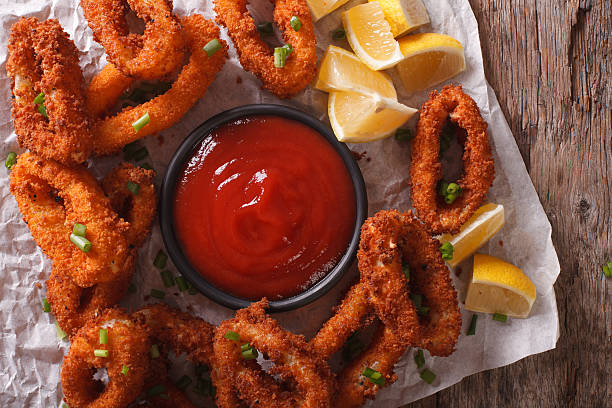 istock Fried calamari close-up on a table, and tomato sauce. horizontal 636600754