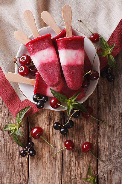 Popsicle with cherry on a stick close-up on the table
