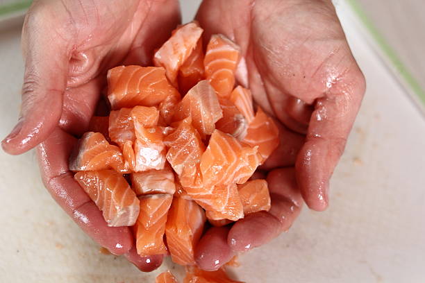 istock Hands with pieces of salmon fillet 636608812