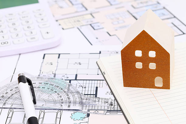 istock Miniature model of house and blueprints 636611408