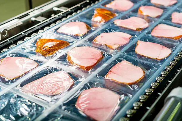 Several chunks of raw meat being processed packaged and shipped