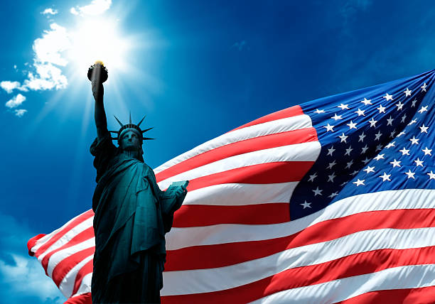 istock statue of liberty and waving american flag 636613992