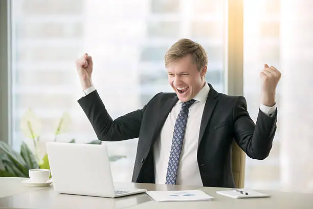 Photo of Young happy businessman at the desk