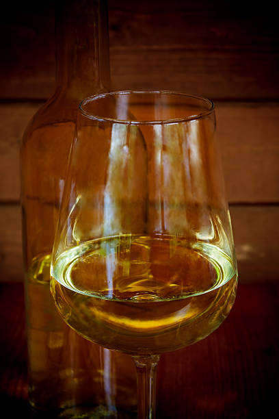 istock Glass of white wine with bottle in background. Selective focus 636621182