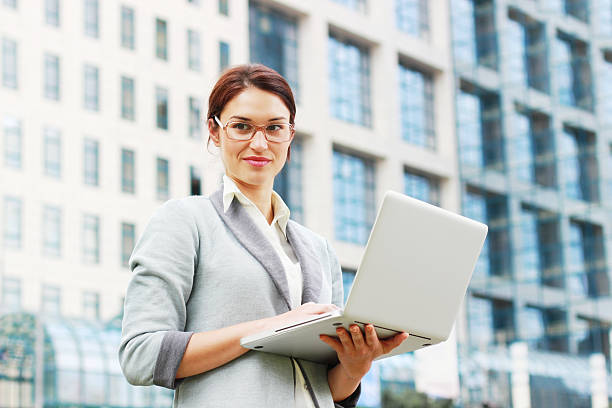 istock Smiling business woman holding laptop 636621302