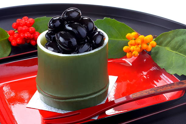 Simmered black soy beans, Japanese New Year’s food One of the Japanese New Year's Osechi dishes in which black beans are sweetly boiled, boiled beans, is photographed with a plant called Nanten that is auspicious. barberry family photos stock pictures, royalty-free photos & images