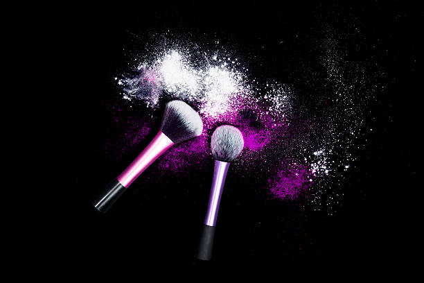 istock Makeup brushes with powder spilled glitter dust on black background. 636629234
