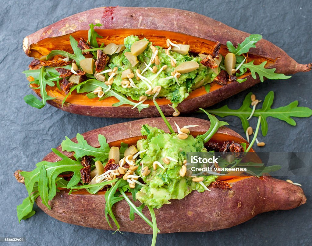 baked sweet potato stuffed A baked sweet potato stuffed with arugula, olives, guacamole. Top view, slate background. Vegan healthy lunch or dinner. Love for a healthy raw food concept. baked sweet potato stuffed with arugula, olives, guacamole. Top view, slate background. Vegan healthy lunch or dinner. Love for a healthy raw food concept. Avocado Stock Photo