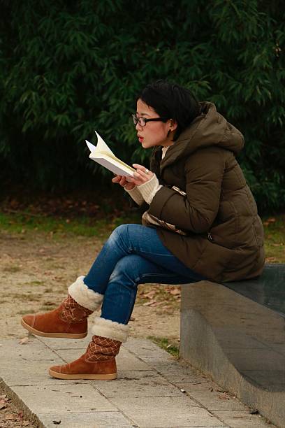 istock Woman reading a book in the park 636635700