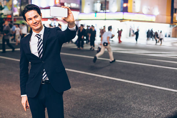 istock Smiling asian businessman making selfie on street by night 636637794