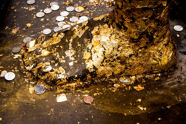 istock Gold leaf taped and coin on Buddha foot statue 636638316
