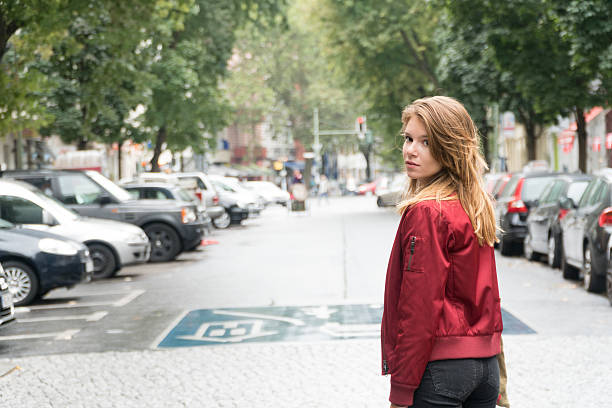 Young woman in Berlin, Germany, sitting at the streetcar station waiting for transportationYoung woman in Berlin, Germany, walking around the city and looking back towards the camera.
