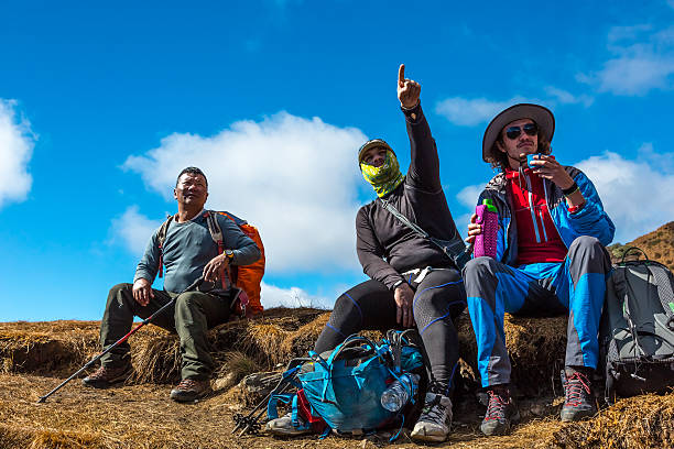 istock Group of Travellers resting on Mountain Footpath pointing Hand forward 636643776