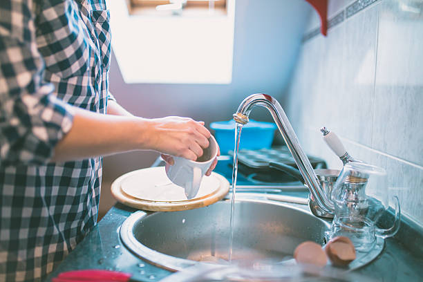 istock Beautiful smiling young woman washing a cup in white kitchen. 636643950