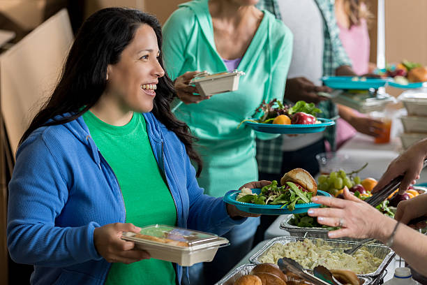 mulher hispânica adulta média recebe refeição na cozinha de sopa - homelessness food in a row people - fotografias e filmes do acervo
