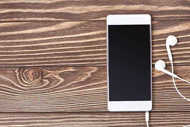 istock Smartphone and headphones on wooden background 636650536