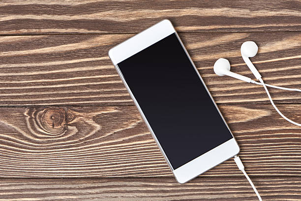 istock Smartphone and headphones on wooden background 636650772