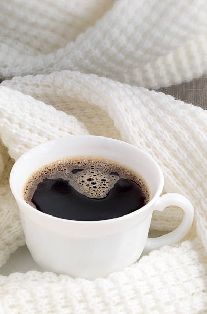 istock White cup with hot coffee wrapped in white woolen scarf 636655138