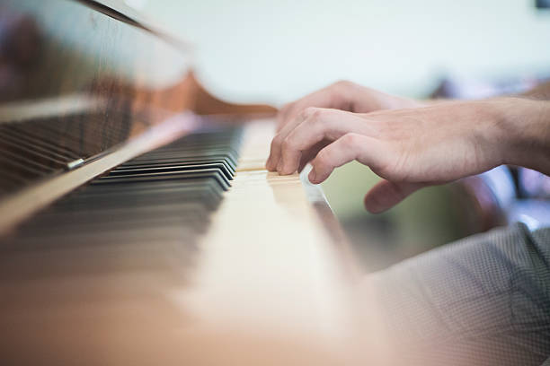 istock Young man playing piano. Closeup hands on keyboard 636658658