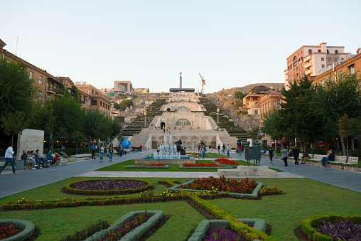 Yerevan, Armenia - October 5, 2016: People enjoy a warm autumn evening at the base of the Cascade, a giant stairway in Yerevan, Armenia. In addition to stairs the Cascade has multiple levels with fountains and sculptures. The Cascade was designed by architects Jim Torosyan, Aslan Mkhitaryan, Sargis Gurzadyan and completed in 1980 when Armenia was part of the Soviet Union.
