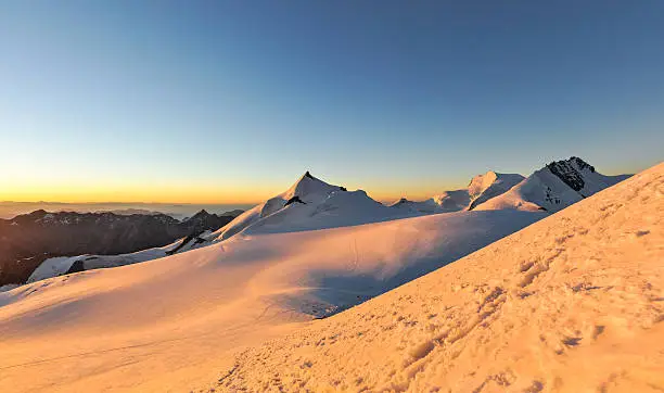 XXL panorama of sunrise at 3800m amsl in the Swiss Wallis Alps near the summit of Alphubel (4206m).Allalinhorn, Strahlhorn & Rimpfischhorn in the background (left to right).Snow fields in foreground.