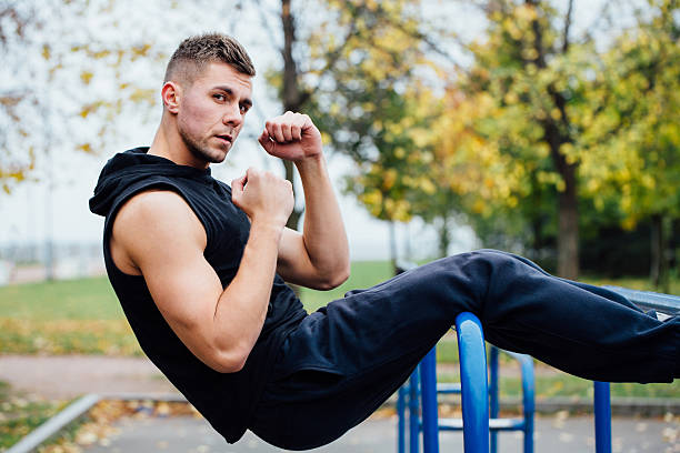 istock Fitness man doing stomach workouts on horizontal bar outdoors 636667196