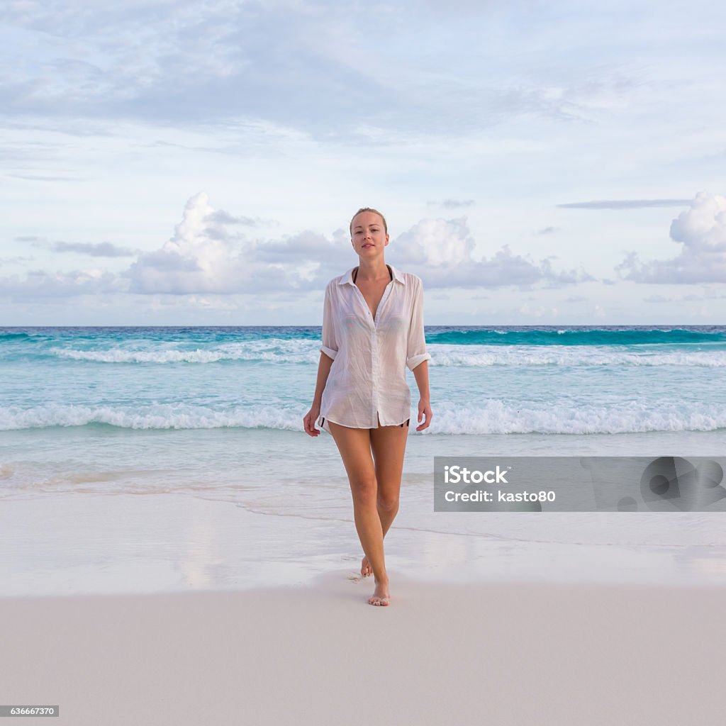 Woman on summer vacations at tropical beach of Mahe Island Woman wearing white loose tunic over bikini on Mahe Island, Seychelles. Summer vacations on picture perfect tropical beach concept. Active Lifestyle Stock Photo