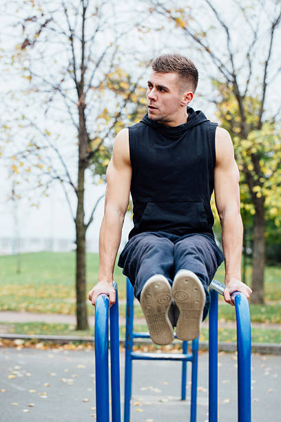 istock Fitness man doing stomach workouts on horizontal bar outdoors 636667756
