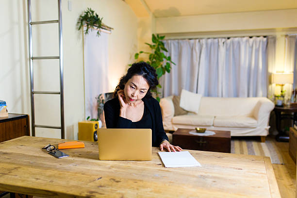 istock Mature woman looking at laptop computer while sitting at table 636668716
