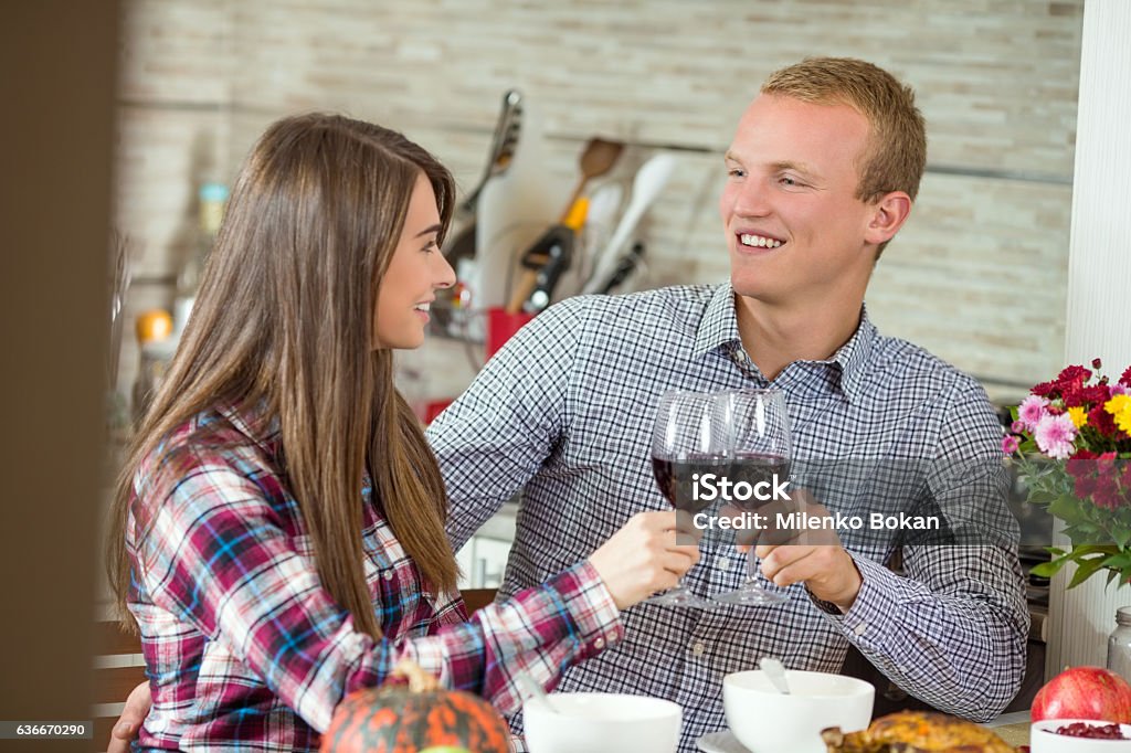 Young Couple Having Dinner at Home Happy young couple is having a romantic holiday dinner at home. They are toasting with wine. Thanksgiving - Holiday Stock Photo