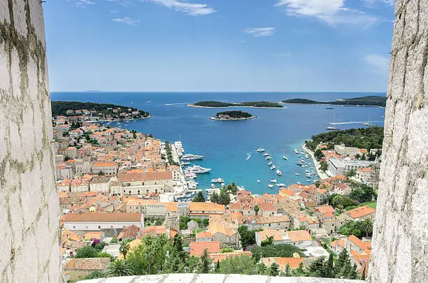 The view of the historic Hvar Town from the lofty heights of the Spanjola (Spanish) Fortress which sits high above the town, in between the battlements, on a summer's day, in a horizontal orientation.