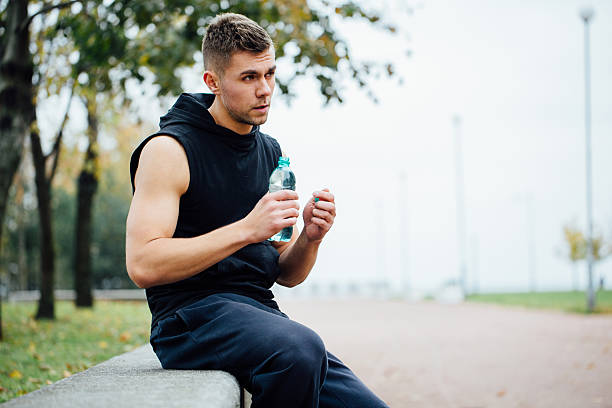 istock Athlete resting on bench in park after running with bottle 636671820