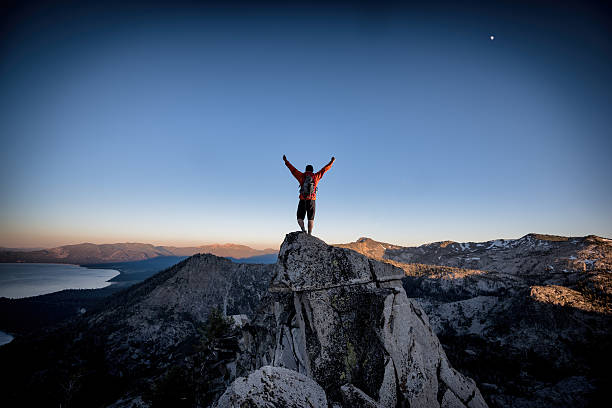Success and Victory in the mountains A climber reaches the summit of an exposed mountain top in the Tahoe backcountry, California winning stock pictures, royalty-free photos & images