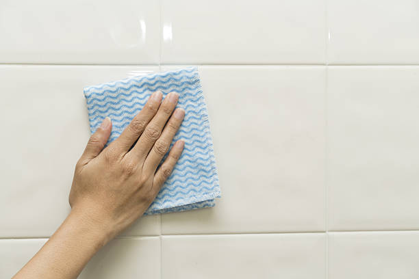 istock Cleaning tile wall by woman hand 636677036